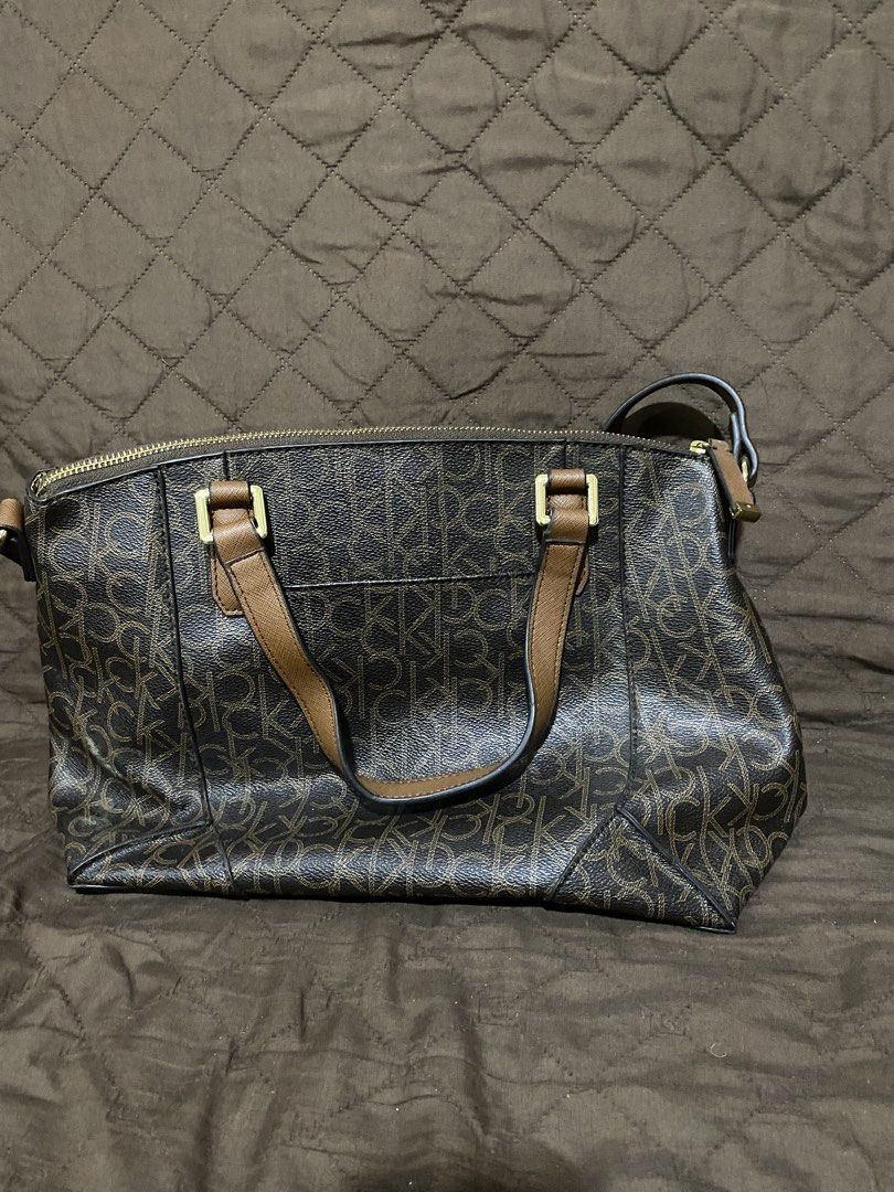 Calvin Klein monogram brown satchel shoulder bag (Category: Shoulder Bags) located in Manila. Submitted by divinemercy_29 (Listing ID 1464893087, Image 2). Description: - Brand: Calvin Klein - Design: Allover CK monogram pattern in brown with contrast tan handles - Strap: Comes with a long adjustable shoulder strap for versatile wear - Hardware: Elegant gold-tone hardware with a stylish brand charm - Closure & Interior: Secure zip-top closure wit