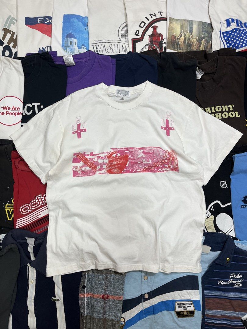 Cav Empt White Graphic Tee Size M (Category: Tshirts & Polo Shirts ) located in Baao. Submitted by plainclothesdept (Listing ID 1464780209, Image 1). Description: Cav Empt Pink Tee width - 21 in. length- 26 in. minimal discoloration near armpit - Brand: Cav Empt - Style: White graphic tee - Size: Medium - Origin: Made in Japan - Design details: Pink front chest graphic, cross branding near the collar, and 'Cav Empt' lettering down both sleeves - 