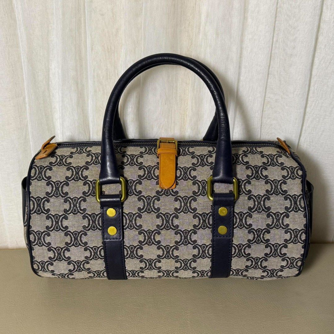 Celine Monogram Barrel Handbag Blue Canvas Leather (Category: Luxury Bags & Wallets) located in Madrid. Submitted by jhunaceee (Listing ID 1464893684, Image 2). Description: - Brand: Celine Vintage - Style: Barrel Bag / Cylinder Shape - Material: Blue monogram canvas with dark & tan leather trim - Hardware: Gold-tone with stud details - Handles: Dual rolled leather top handles - Pockets: Convenient end slip pocket with button snap closure - Struc