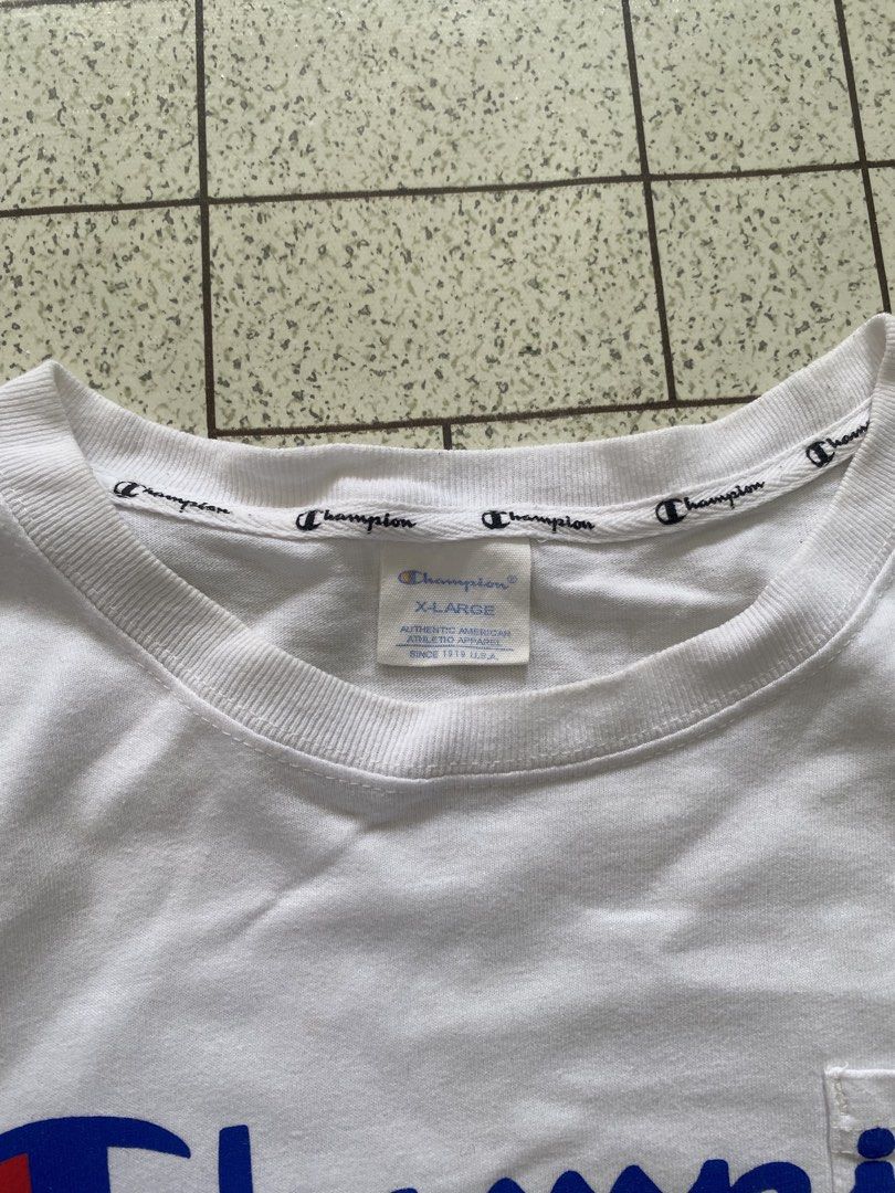 Champion White Script Logo Pocket T-Shirt X-Large (Category: Tshirts & Polo Shirts ) located in Manila. Submitted by sepamorash53558 (Listing ID 1464807467, Image 3). Description: - Brand: Champion - Color: White - Size: X-Large (XL) - Features: Large blue script logo, chest pocket, left sleeve embroidered patch, and branded inner collar tape - Measurements: ~21" pit-to-pit, ~27.5" length - Condition: Excellent.