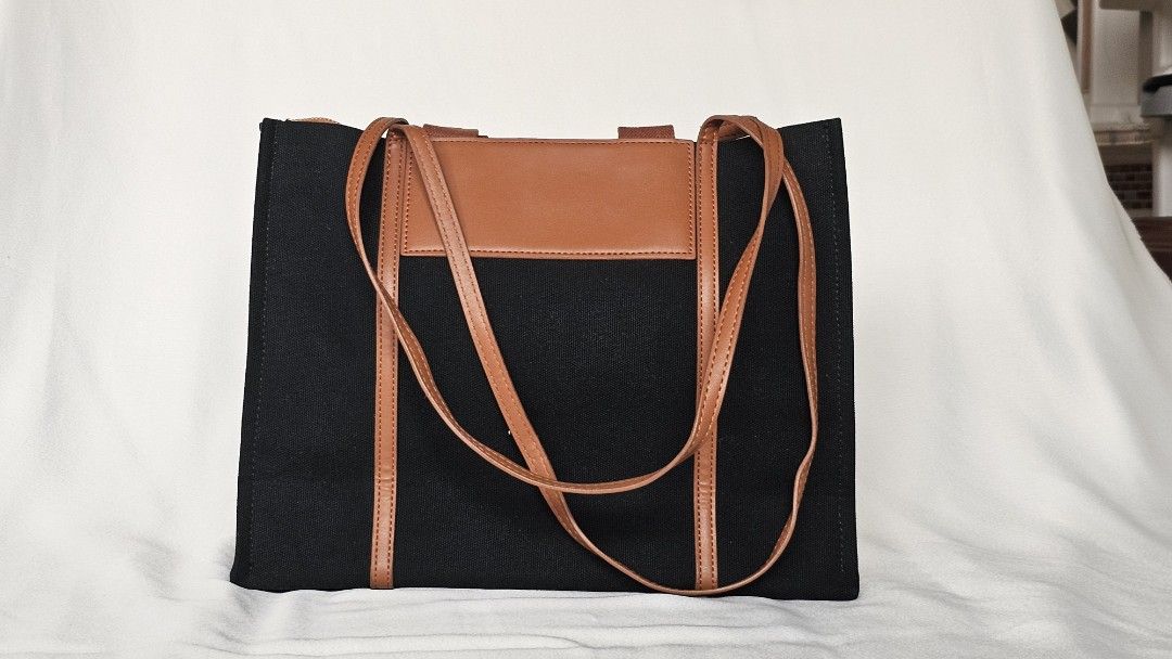 Charles & Keith Black and Brown Tote Bag (Category: Tote Bags) located in Quezon. Submitted by cgmhe (Listing ID 1464823341, Image 3). Description: - Brand: Charles & Keith - Material: Black canvas with brown faux leather trim - Closure: Secure zip top - Interior: Spacious with a convenient zipper pocket - Details: Debossed logo on front patch and sturdy dual handles - Condition: Clean fabric and sturdy construction.
