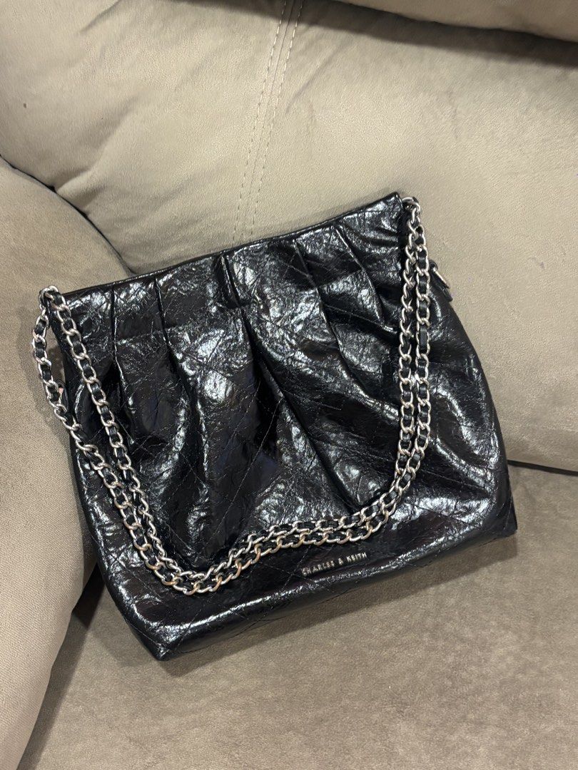Charles & Keith Black Quilted Chain Shoulder Bag (Category: Shoulder Bags) located in Andop. Submitted by pinkmatcha0715 (Listing ID 1464962610, Image 1). Description: - Brand: Charles & Keith - Style: Shoulder bag with edgy crinkled patent finish and quilted pattern - Straps: Double chain strap woven with black material - Hardware: Silver-toned with subtle stamped logo near the base - Interior: Open top design with an internal zip pocket lining 