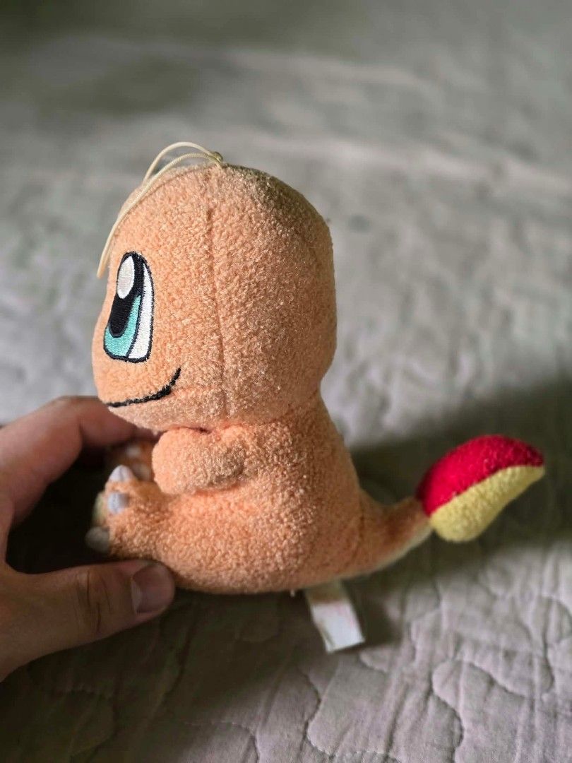 Charmander Pokemon Mini Plush Toy (Category: Plushies & Soft Toys) located in Baguio. Submitted by je_ver_lyn16 (Listing ID 1464845725, Image 2). Description: - 6-inch sitting Charmander plush toy - Features embroidered blue and black eyes - Classic red and yellow flame tail design - Includes a small hanging string on top of the head - Comes with an attached tag underneath - Made with clean, super soft fabric.