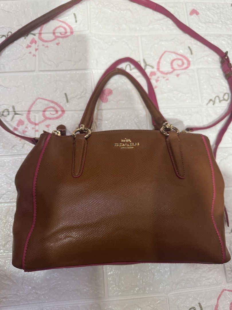 Coach Brown Leather Handbag with Pink Trim (Category: Luxury Bags & Wallets) located in Manila. Submitted by wildbear.e10374 (Listing ID 1464806010, Image 1). Description: Coach leather handbag in brown with vibrant pink trim and piping details. Gold-toned hardware and Coach logo stamped on the front. Dual top handles plus a detachable shoulder strap included. Multiple interior compartments lined in pink fabric with zipper pockets. Structured bas