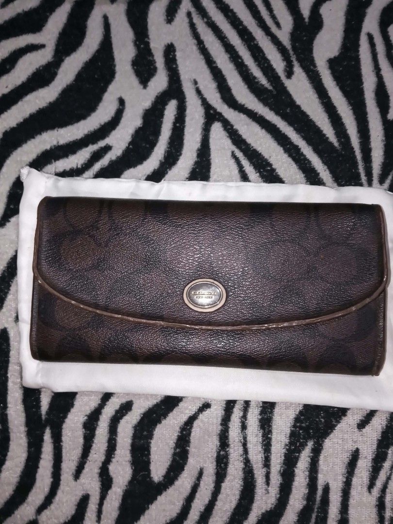 Coach Brown Signature Monogram Long Wallet (Category: Luxury Bags & Wallets) located in Valenzuela. Submitted by rowenasalvador777 (Listing ID 1464968601, Image 1). Description: - Authentic brown Coach long wallet - Classic signature monogram print with dark brown trim - Front flap closure with distinctive oval metallic Coach logo medallion - Slim profile that fits easily into any handbag - Ample interior space for cards and cash - Condition: Exc