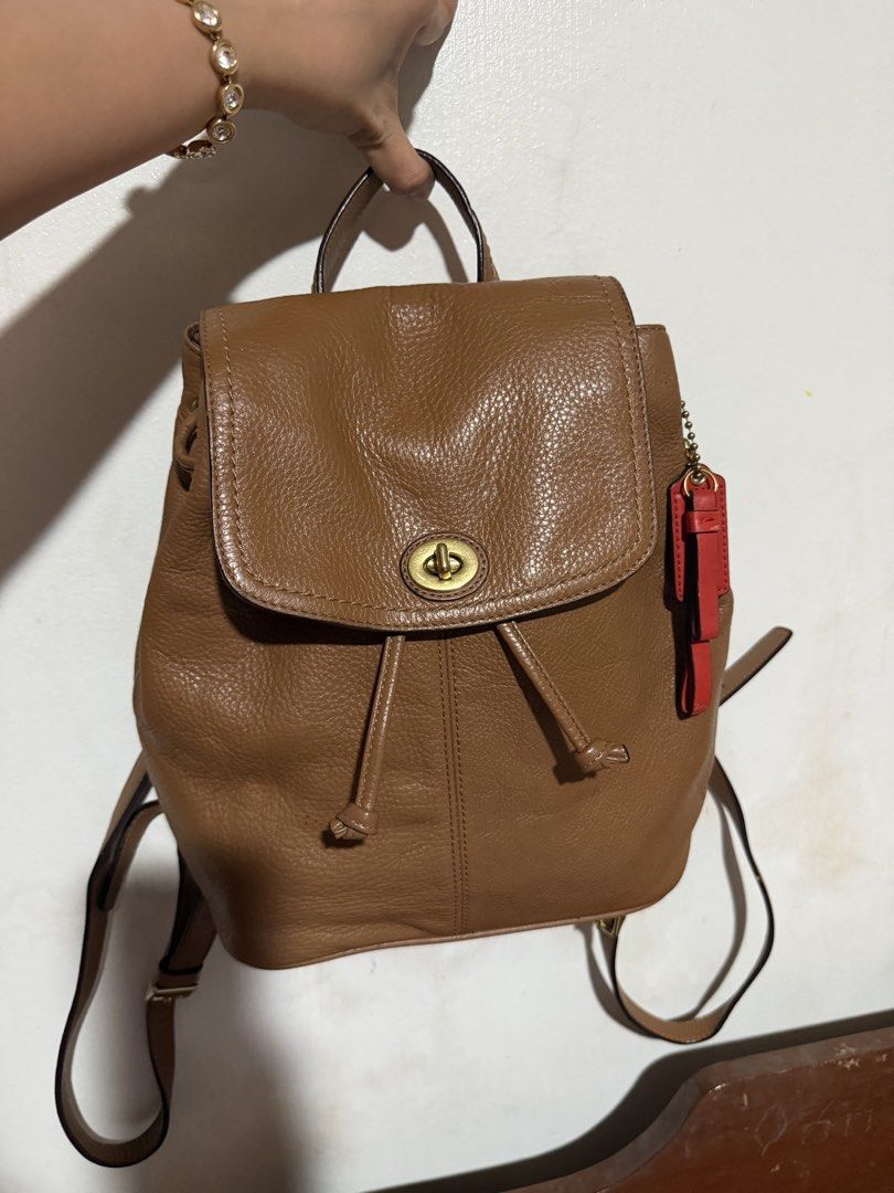 Coach Brown Leather Park Backpack with Red Hangtag (Category: Backpacks) located in San Pablo. Submitted by prelovedbymistyblue (Listing ID 1464825034, Image 1). Description: - Authentic Coach brown pebbled leather backpack - Classic turnlock closure and secure drawstring top - Adjustable shoulder straps and convenient top handle - Stylish vertical front seam detail - Includes signature bright red Coach hangtag - Clean interior and well-maintaine