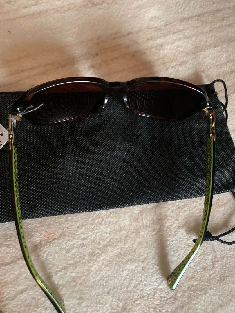 Coach Sunglasses 135 Size with Dust Bag (Category: Sunglasses & Eyewear) located in Caloocan City. Submitted by nobleflower_4c42cc (Listing ID 1464805373, Image 2). Description: - Brand: Coach - Size: 135 - Design: Tortoise shell frames with green patterned arms and gold chain link details - Condition: Lenses have zero scratches, original tag still attached - Inclusions: Black protective dust bag - Ideal for: Stylish everyday sun protection.