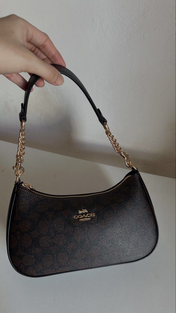 Coach Teri (Category: Shoulder Bags) located in Manila. Submitted by obbusemer38788 (Listing ID 1464829106, Image 3). Description: - Authentic Coach shoulder bag in classic brown signature coated canvas - Chic black leather trim along the base and sides for added durability - Elegant gold-tone hardware featuring stylish chain strap links - Secure zip-top closure with a metal pull - Clean and well-kept both inside and out.