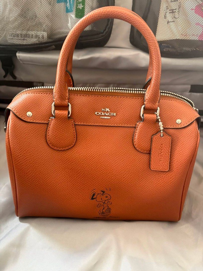 Coach x Peanuts Snoopy Orange Satchel Handbag (Category: Luxury Bags & Wallets) located in Muntinlupa City. Submitted by koi_143 (Listing ID 1464847625, Image 1). Description: - Authentic Coach satchel in vibrant textured orange leather - Adorable Snoopy graphic printed near the bottom front - Sleek silver-tone hardware and matching leather hangtag - Convenient double top handles and secure top zip closure - Impeccable, clean interior and exterio