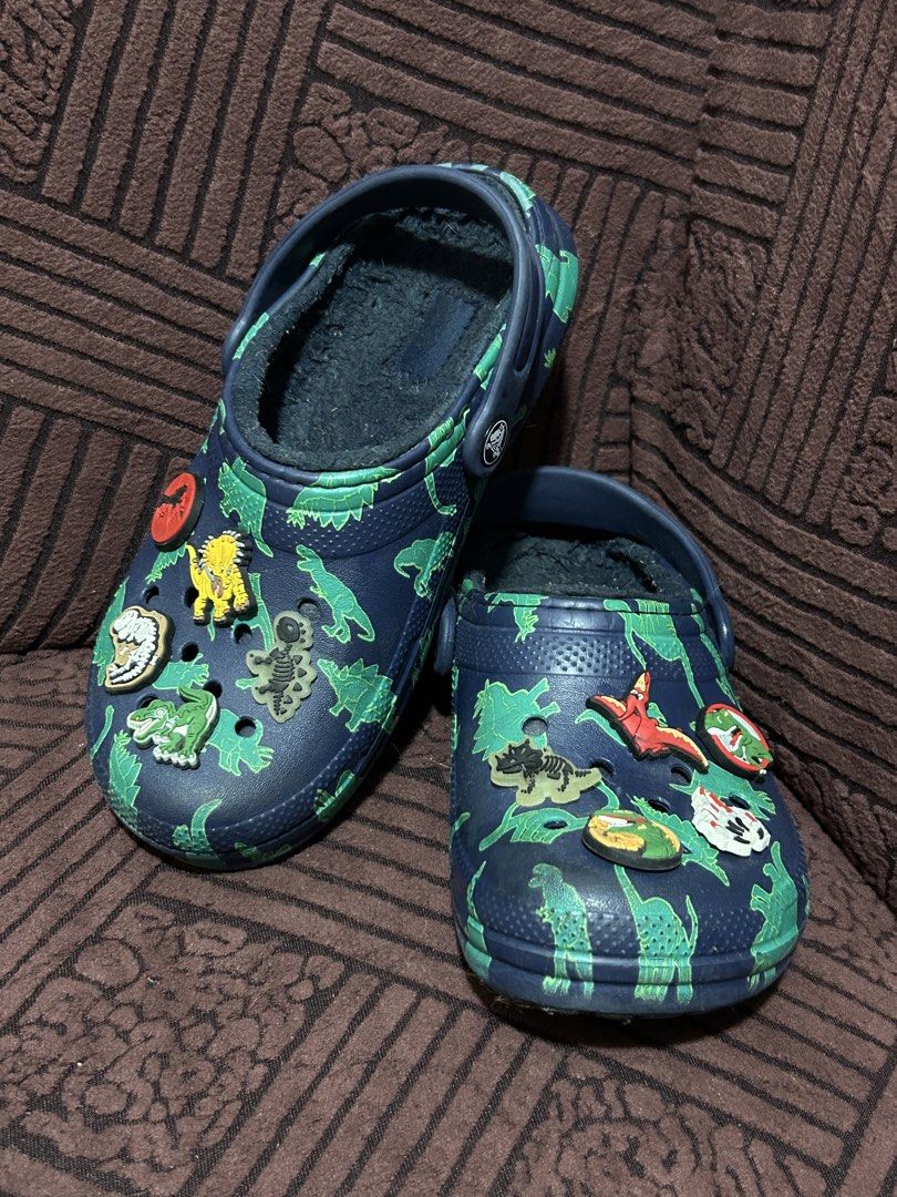 Crocs Dinosaur Lined Clogs with Jibbitz Charms (Category: Babies & Kids Fashion) located in Binan City. Submitted by lehcarsmusthaves (Listing ID 1464948017, Image 1). Description: - Color & Design: Navy blue with an all-over green dinosaur print - Warmth: Cozy fuzzy lining inside, perfect for cooler days - Extras: Comes with fun dinosaur Jibbitz charms already attached - Fit: Easy slip-on design with a pivoting heel strap Free jibbits (has 2 lum