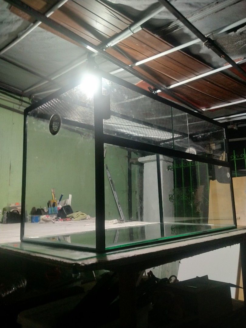 Custom large size enclosure (Category: Homes & Other Pet Accessories) located in Binan City. Submitted by scuteriztha (Listing ID 1464878129, Image 3). Description: - Type: Glass terrarium with heavy-duty black metal frame - Ventilation: Mesh top and built-in side ventilation port - Access: Convenient sliding glass doors at the front - Condition: Clean glass panes and solid build - Best For: Reptiles, amphibians, or lush planted setups.