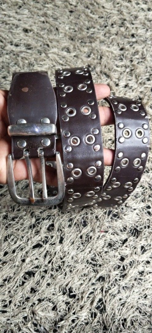Dark Brown Grommet Studded Leather Belt (Category: Belts) located in Paranaque City. Submitted by michael-08 (Listing ID 1464782676, Image 1). Description: - Style: Punk rock aesthetic, dark brown leather belt - Hardware: Silver grommets, metal studs, and heavy metal double-prong buckle with aged silver finish - Dimensions: Roughly 1.5 inches wide - Condition: Sturdy construction with a small spot mark on the leather near the top buckle area - Fe