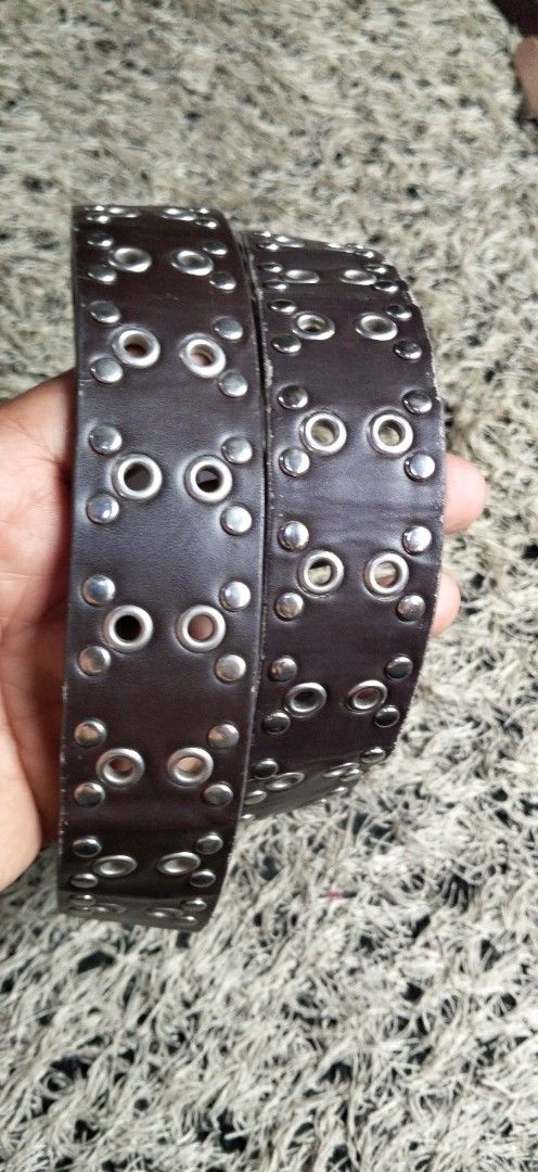 Dark Brown Grommet Studded Leather Belt (Category: Belts) located in Paranaque City. Submitted by michael-08 (Listing ID 1464782676, Image 2). Description: - Style: Punk rock aesthetic, dark brown leather belt - Hardware: Silver grommets, metal studs, and heavy metal double-prong buckle with aged silver finish - Dimensions: Roughly 1.5 inches wide - Condition: Sturdy construction with a small spot mark on the leather near the top buckle area - Fe