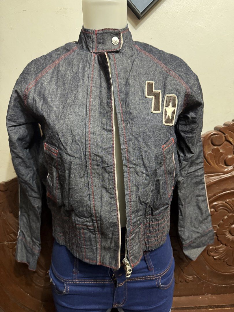 Denim Bomber Jacket with Star Patch and Contrast Stitching (Category: Coats, Jackets and Outerwear) located in Marikina City. Submitted by lorradel (Listing ID 1464829264, Image 1). Description: - Dark denim bomber jacket with striking red contrast stitching - High neck collar with a snap button closure - Full front zipper and practical slanted front pockets - Comfortable ribbed elastic hem and cuffs - Stylish embroidered star patch and number de