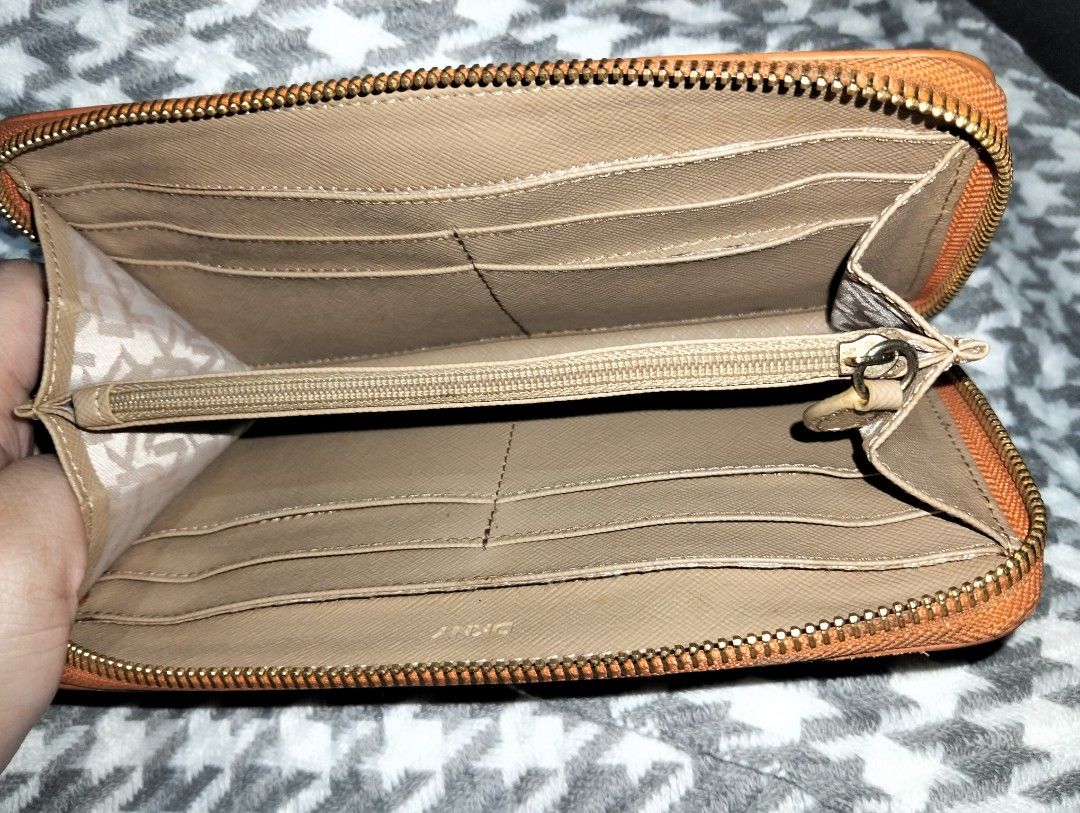 DKNY Orange Zip-Around Leather Wallet (Category: Wallets & Card holders) located in Caloocan City. Submitted by girlshopmcollection (Listing ID 1464870414, Image 3). Description: - Brand: DKNY - bright orange - Hardware: Gold-tone with metal front logo - Interior: Tan with multiple card slots, slip pockets, and central zippered coin compartment - Lining: Clean with repeating logo pattern - Closure: Smooth zip-around.