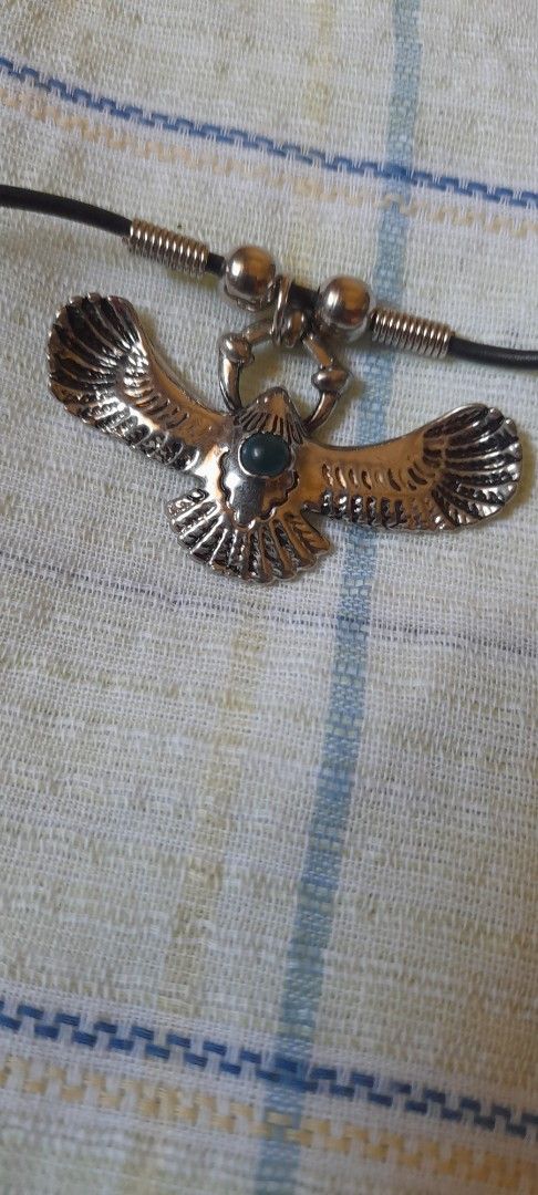 Eagle Pendant Necklace with Black Cord (Category: Necklaces) located in Bocaue. Submitted by marajapansurplus (Listing ID 1464772351, Image 3). Description: - Design: Silver-toned metal eagle pendant with textured wings and a dark central stone - Closure: Black cord choker with spring ring clasp - Size: Standard choker length - Condition: Hardware shows minor wear on the back side - Style: Great statement piece for casual outfits.