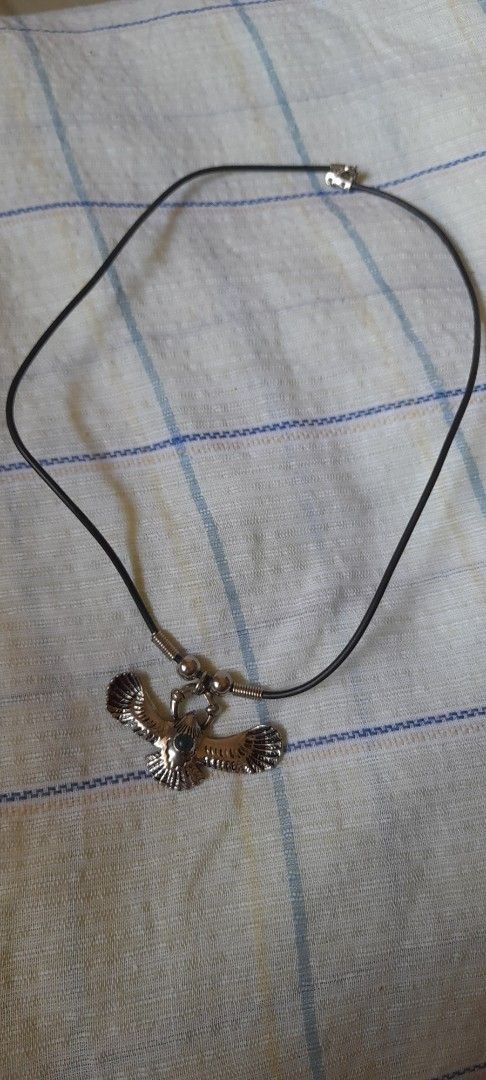 Eagle Pendant Necklace with Black Cord (Category: Necklaces) located in Bocaue. Submitted by marajapansurplus (Listing ID 1464772351, Image 2). Description: - Design: Silver-toned metal eagle pendant with textured wings and a dark central stone - Closure: Black cord choker with spring ring clasp - Size: Standard choker length - Condition: Hardware shows minor wear on the back side - Style: Great statement piece for casual outfits.