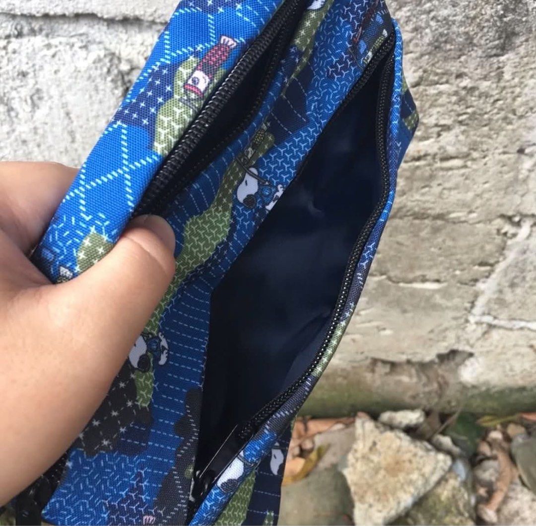 FDMTL x Peanuts (Category: Sling Bags) located in Rizal. Submitted by timelessfinds89_ (Listing ID 1464916755, Image 3). Description: - Brand: FDMTL x Peanuts Collaboration - Design: Blue camouflage with iconic Snoopy and carp streamer graphics - Compartments: Secure main zip opening plus two front zip pockets - Interior: Clean dark blue lining - Strap: Comfortable, adjustable black cord strap - Details: Signature woven brand patch on the lower f