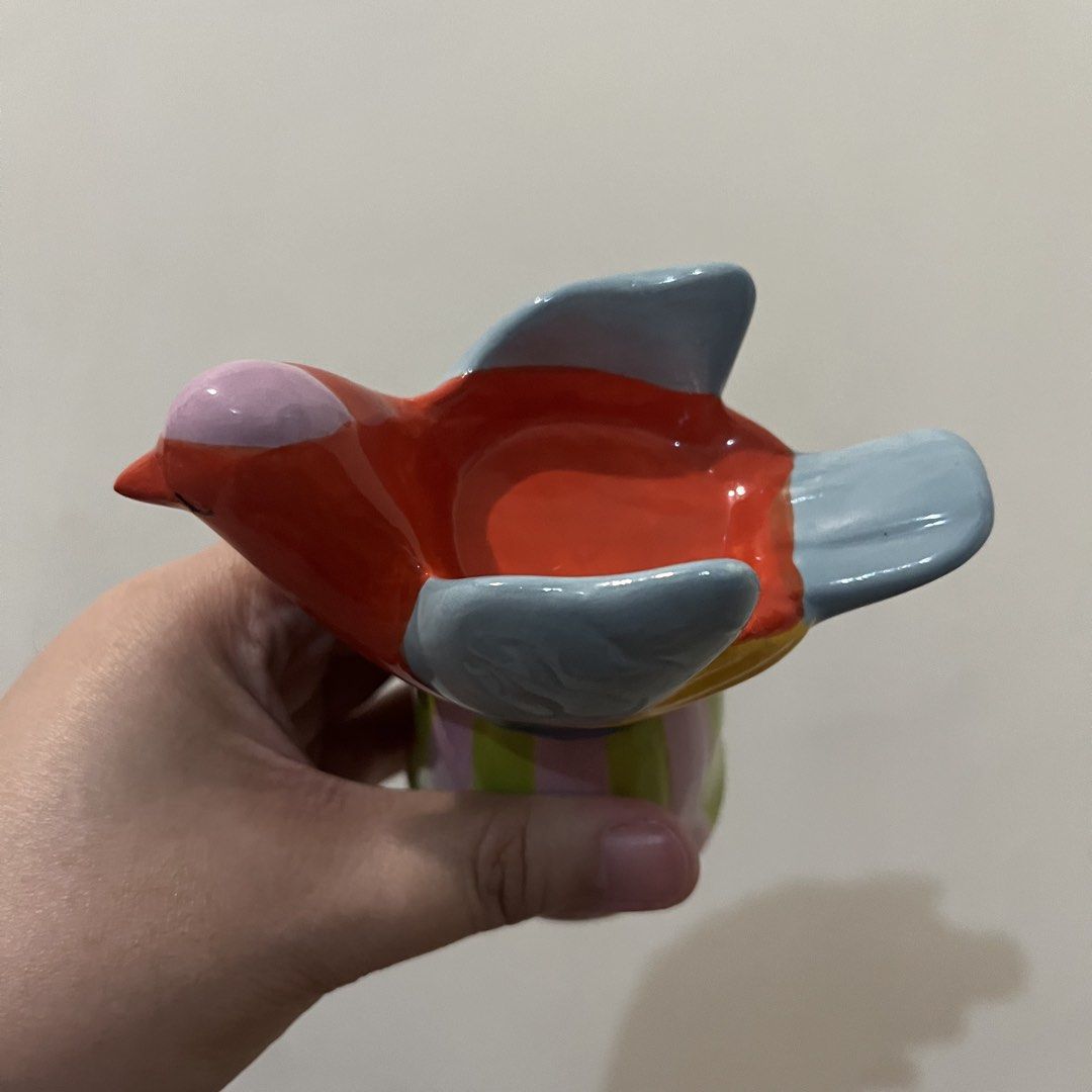 Flying Tiger Copenhagen Ceramic Bird Figurine Holder (Category: Vases & Decorative Bowls) located in San Pedro. Submitted by rainyydayy (Listing ID 1464856921, Image 3). Description: - Brand: Flying Tiger Copenhagen - Material: Glossy ceramic - Design: Multicolor bird with red head, blue wings, and striped pink-and-green base - Function: Decorative piece or small trinket tray with open top - Authenticity: Bottom stamped with Zebra A/S branding an