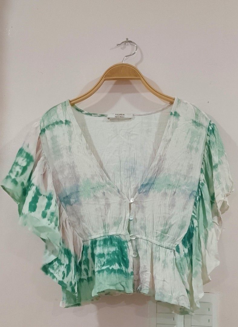 Green and white tie-dye crop blouse from Pull&Bear (Category: Blouses) located in Cabanatuan. Submitted by miss.maia (Listing ID 1464947649, Image 2). Description: The image shows a green and white tie-dye crop blouse from Pull&Bear featuring a deep V-neck, front button closure, and short ruffled sleeves..