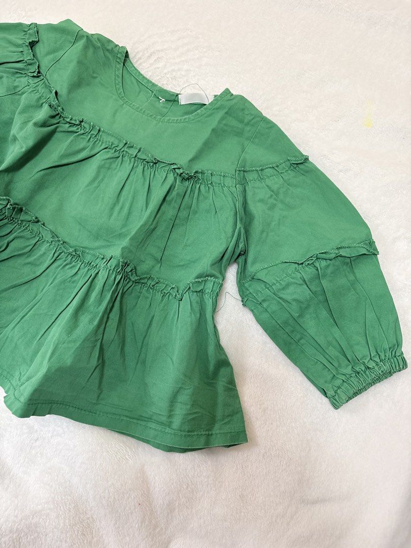 Green Tiered Ruffle Long Sleeve Blouse (Category: Babies & Kids Fashion) located in Cabuyao City. Submitted by mhd.i (Listing ID 1464968400, Image 2). Description: - Color: Bright green - Design: Three-layer gathered tiered design with shoulder ruffles - Sleeves: Long sleeves with elastic ruffled cuffs - Neckline: Round neckline - Fit: Relaxed fit through the body - Fabric: Lightweight and comfortable - Styling: Easy to pair with jeans or skirts.