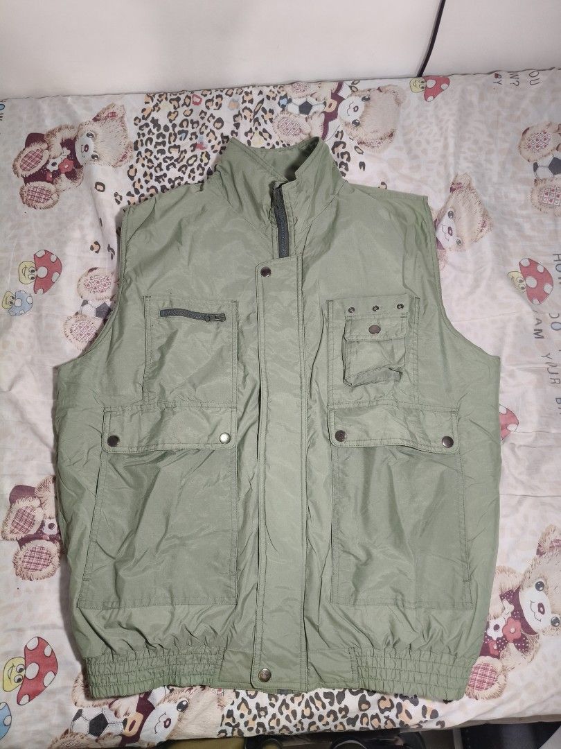 Green Utility Puffer Jacket Vest (Category: Coats, Jackets and Outerwear) located in Lapu Lapu. Submitted by hooman422 (Listing ID 1464914709, Image 1). Description: • Style: Multi-pocket utility or tactical gilet vest. • Color: Light sage green or olive drab. • Material: Lightweight, durable synthetic nylon or polyester fabric. • Closure: Front zipper closure with a buttoned storm flap. • Collar: High stand-up mock neck collar. • Pockets: Featur
