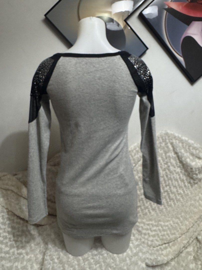 Grey Long Sleeve Top with Rhinestone Shoulders (Category: Longsleeves) located in Marikina City. Submitted by lorradel (Listing ID 1464894522, Image 3). Description: - fits S-M - Style: Fitted long sleeve top with a hip-length cut - Color: Grey with black trim along the scoop neckline - Details: Rhinestone embellishments and sheer fabric panels on shoulders and upper sleeves - Graphic: Rhinestone script lettering across the front chest - Material