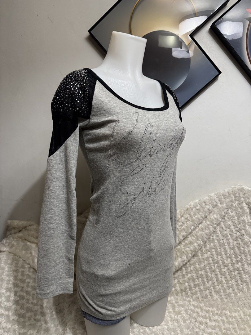 Grey Long Sleeve Top with Rhinestone Shoulders (Category: Longsleeves) located in Marikina City. Submitted by lorradel (Listing ID 1464894522, Image 2). Description: - fits S-M - Style: Fitted long sleeve top with a hip-length cut - Color: Grey with black trim along the scoop neckline - Details: Rhinestone embellishments and sheer fabric panels on shoulders and upper sleeves - Graphic: Rhinestone script lettering across the front chest - Material