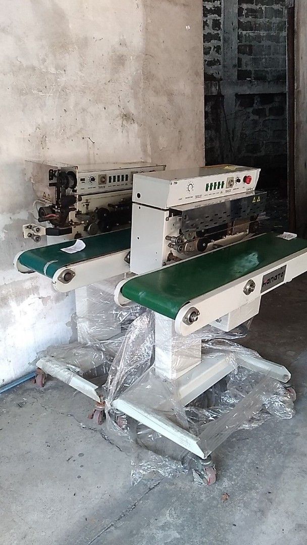 Hanato Continuous Band Sealer Machine Industrial Packaging Equipment (Category: Industrial Equipment) located in Quezon City. Submitted by nhatedaniel2293164 (Listing ID 1464932639, Image 1). Description: - Set of 6 heavy-duty continuous band sealer machines - Equipped with green conveyor belts and sturdy white metal stands - Includes caster wheels for easy mobility in the warehouse - Top-mounted control panels with user-friendly dials and switch