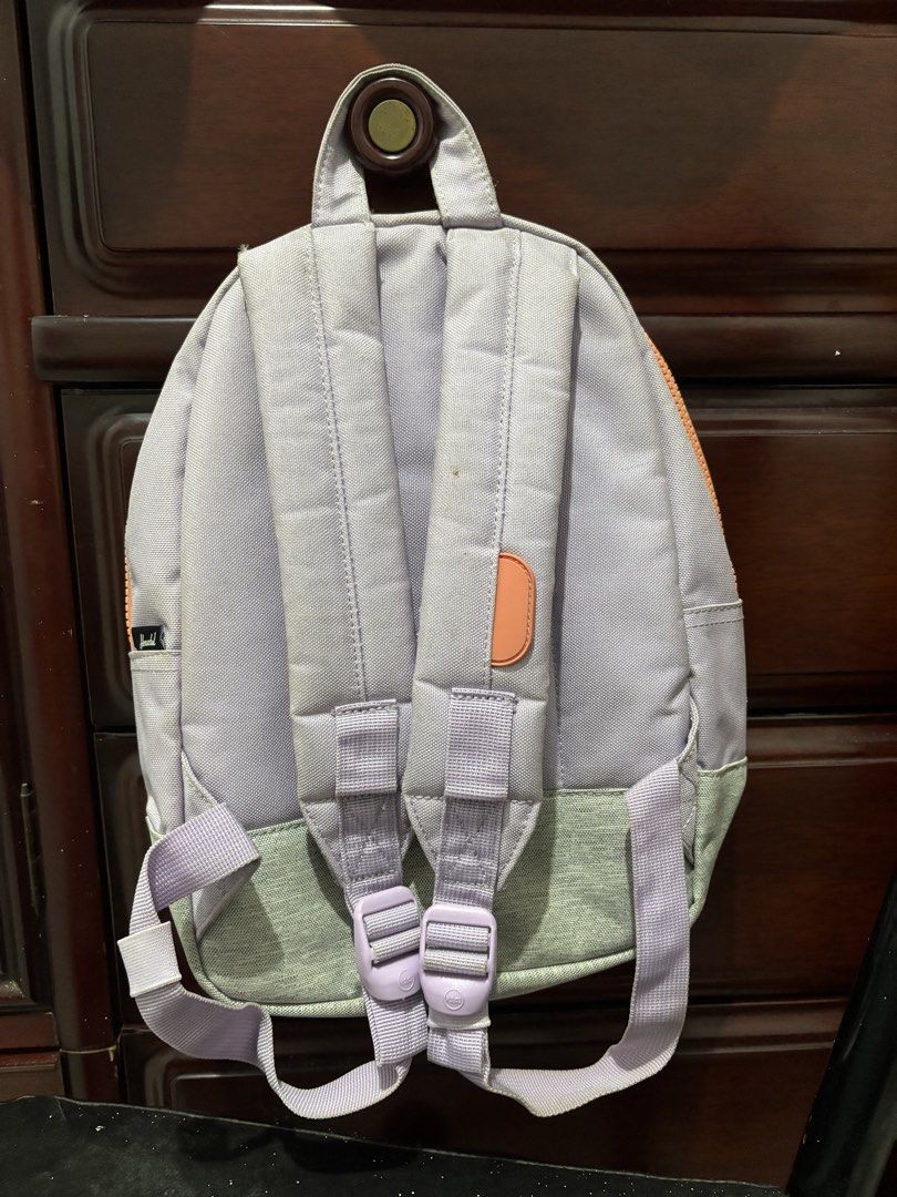Herschel Supply Co. Heritage Kids Backpack Multi-color (Category: Backpacks) located in Manila. Submitted by amphitrite_ (Listing ID 1464780639, Image 3). Description: - Brand: Herschel Supply Co. - Colorway: Lavender, orange, and grey - Exterior: Front zippered pocket, iconic logo patch, and stylish leather diamond accent - Interior: Signature red and white striped lining with a built-in name label slot - Comfort: Padded, adjustable shoulder str