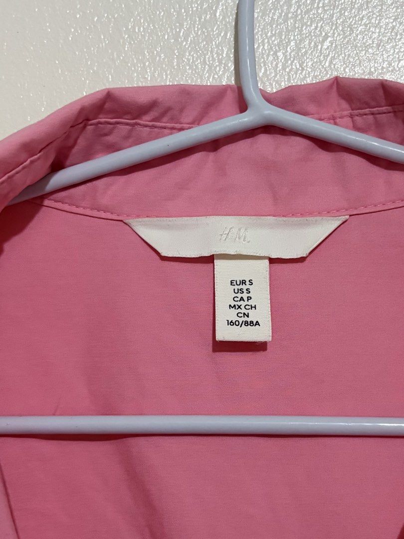 H&M Pink Button-Down Long Sleeve Shirt Size S (Category: Longsleeves) located in Cainta. Submitted by knarv__ (Listing ID 1464881802, Image 3). Description: Bright pink H&M button-down shirt in Size S. Features long sleeves, a classic collar, and a trendy high-low hem. Made of soft cotton. Please note: there are noticeable bleach stains on the chest, lower placket, and right cuff. Great price for a stylish piece!.