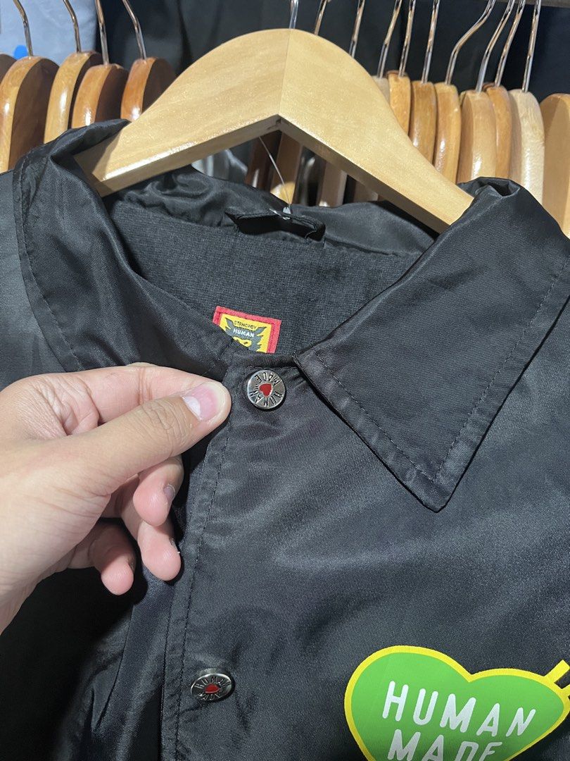 Human Made Black Coach Jacket Size L (Category: Coats, Jackets and Outerwear) located in Davao. Submitted by erwin_james (Listing ID 1464889077, Image 3). Description: - Brand: Human Made (by Nigo) - Style: Black coach jacket with collared neckline and snap button closure - Size: Large - Design: Large green heart graphic with white branding on the back, matching green heart on the left chest - Details: Features inner lining and authentic tag bran