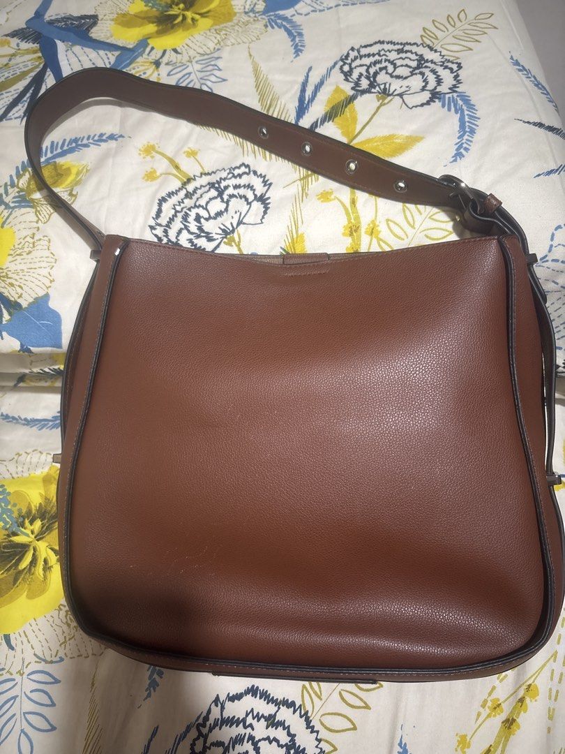 Hush Puppies Brown Shoulder Bag (Category: Shoulder Bags) located in Quezon City. Submitted by relyncabubas (Listing ID 1464782942, Image 2). Description: - Brand: Hush Puppies - Material: Textured faux leather in brown - Strap: Adjustable with stylish metal buckle details - Closure: Secure zip and magnetic snap main compartment - Interior: Clean black fabric lining - Condition: Clean exterior and interior, great for everyday use.