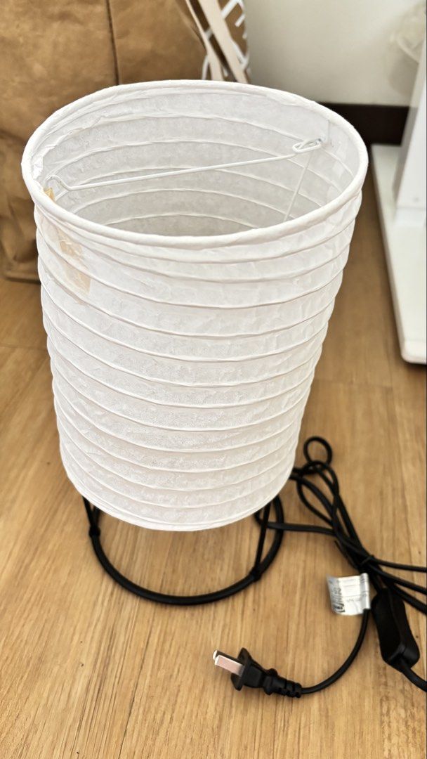 IKEA Paper Lantern Table Lamp with Black Base (Category: Lighting) located in Marikina City. Submitted by majojojojoe (Listing ID 1464833652, Image 1). Description: - Design: Cylindrical paper lantern on a sleek black metal wire base - Ambiance: Emits a warm, cozy glow ideal for bedside tables or desks - Power: Standard power cord equipped with an easy-to-use inline switch and plug - Condition: Fully functional; minor imperfection with one small 