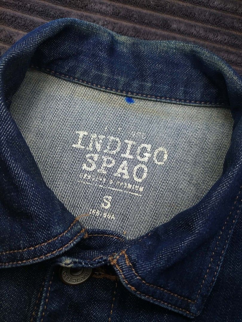 Indigo Spao Denim Jacket Size S (Category: Coats, Jackets and Outerwear) located in Manila. Submitted by norathrifted (Listing ID 1464802454, Image 3). Description: - Brand: Spao - Color: Indigo / Dark blue wash - Size: S - Style: Classic trucker denim jacket - Details: Metal buttons embossed with 'basic 1980' text, contrast orange stitching - Pockets: Two chest flap pockets and two side welt pockets - Condition: Excellent pre-loved condition - M