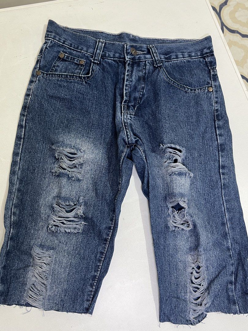 Jagthug Ripped Blue Denim Jeans (Category: Jeans) located in Manila. Submitted by sennisen (Listing ID 1464924901, Image 1). Description: - Brand: Jagthug - Style: Blue denim jeans with heavy distress and ripped details - Wash: Dark wash with intentional fading on the thighs - Features: Frayed hems, classic button fly closure, metal hardware, and standard pockets - Details: Red brand label stitched near the waistband - Condition: Excellent, trend