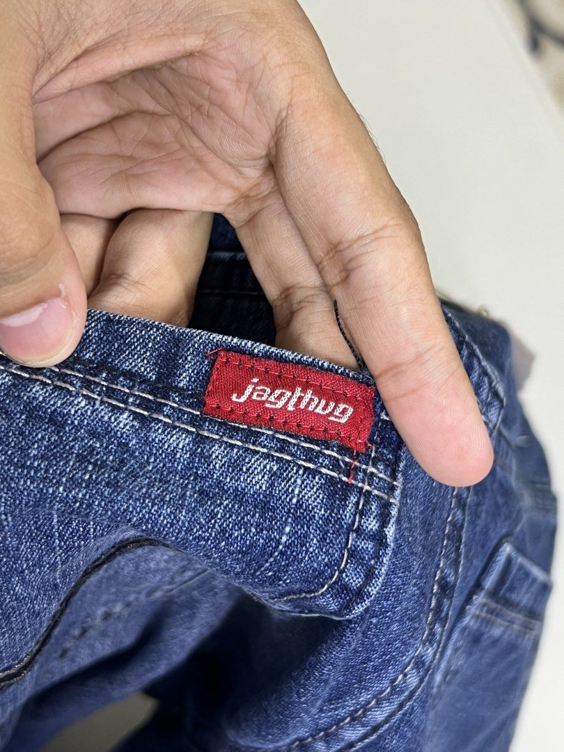 Jagthug Ripped Blue Denim Jeans (Category: Jeans) located in Manila. Submitted by sennisen (Listing ID 1464924901, Image 3). Description: - Brand: Jagthug - Style: Blue denim jeans with heavy distress and ripped details - Wash: Dark wash with intentional fading on the thighs - Features: Frayed hems, classic button fly closure, metal hardware, and standard pockets - Details: Red brand label stitched near the waistband - Condition: Excellent, trend