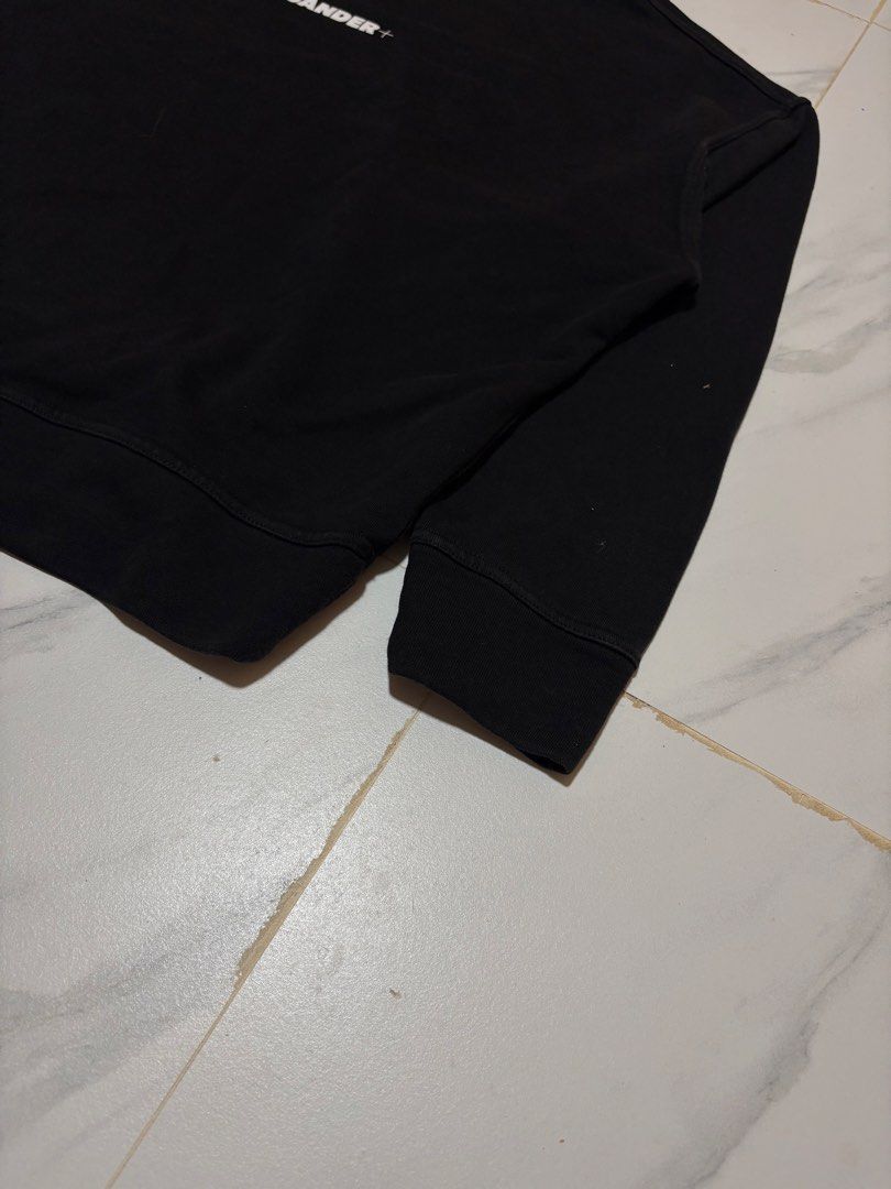Jil Sander+ Black Logo Sweatshirt (Category: Coats, Jackets and Outerwear) located in Baguio. Submitted by thriftedbaguio (Listing ID 1464831635, Image 3). Description: Excellent Condition Size Large Tagged Dimensions 25*25 Color rate 10 - Brand: Jil Sander+ - Color: Black - Material: 100% heavy cotton - Origin: Made in Italy - Design: Classic crewneck with subtle white chest logo - Details: Ribbed cuffs and hem - Condition: Clean, premium piece.