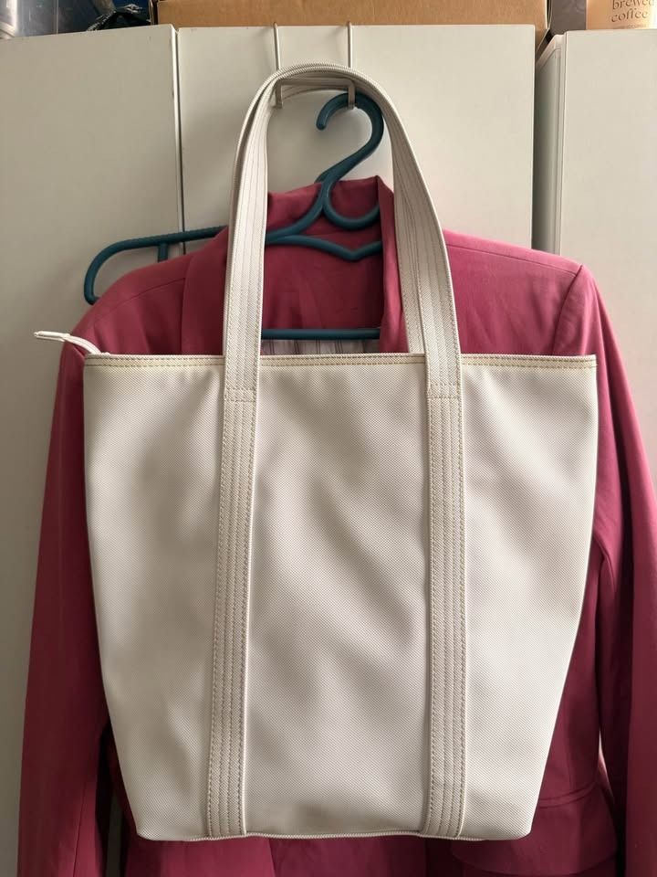 Lacoste Off-White Canvas Tote Bag Vertical (Category: Tote Bags) located in Caloocan City. Submitted by clemg6 (Listing ID 1464784273, Image 2). Description: - Authentic Lacoste white canvas tote bag - Structured rectangular base with sturdy dual shoulder straps - Secure zip top closure - Vibrant yellow interior lining with a leather Lacoste brand patch - Clean exterior fabric showing minimal wear - Perfect for daily use or casual outings 15x13x4