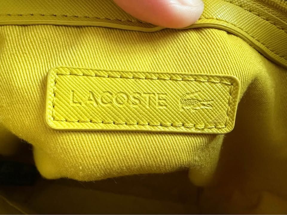 Lacoste Off-White Canvas Tote Bag Vertical (Category: Tote Bags) located in Caloocan City. Submitted by clemg6 (Listing ID 1464784273, Image 3). Description: - Authentic Lacoste white canvas tote bag - Structured rectangular base with sturdy dual shoulder straps - Secure zip top closure - Vibrant yellow interior lining with a leather Lacoste brand patch - Clean exterior fabric showing minimal wear - Perfect for daily use or casual outings 15x13x4