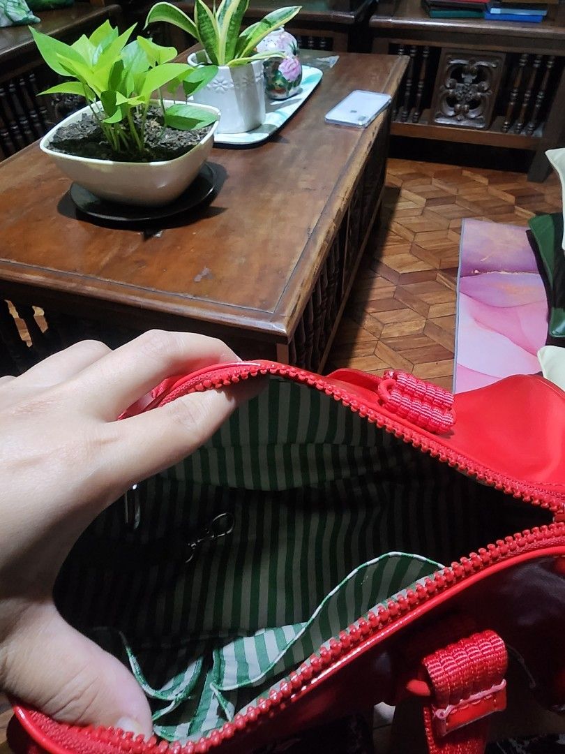 Lacoste Red Vinyl Crossbody Bag (Category: Cross-body Bags) located in Dasmarinas. Submitted by my_preloved_kabinet (Listing ID 1464814967, Image 2). Description: - Brand: Lacoste - Material: Glossy vinyl in vibrant red - Features: Dual red webbed handles, matching detachable shoulder strap with metal clasps, iconic green crocodile logo patch - Interior: Green and white striped fabric lining with a secure zipper closure and round Lacoste pull - C