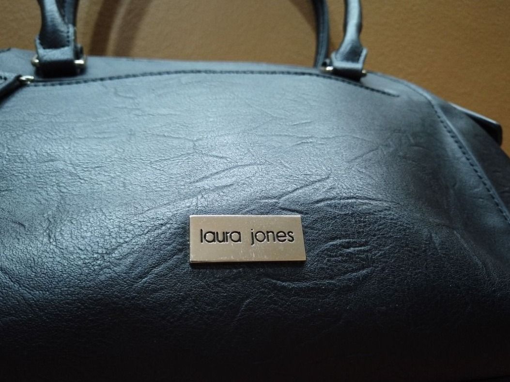 Laura Jones Black Handbag (Category: Shoulder Bags) located in Quezon City. Submitted by cataleya0723 (Listing ID 1464895188, Image 3). Description: - Brand: Laura Jones - Color: Classic Black - Features: Top handles, secure zippered main compartment, and exterior side zippered pocket - Exterior Detail: Small metal brand plaque at the base - Interior: Stylish black-and-white striped fabric lining with slip pockets for organization - Size: Perfect