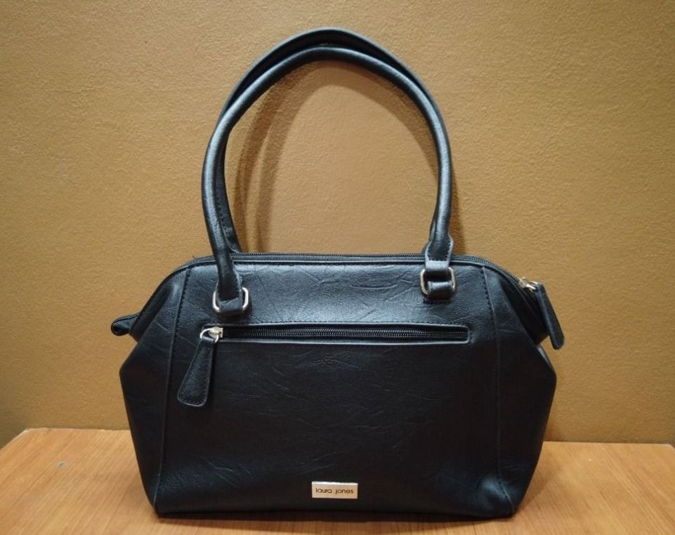 Laura Jones Black Handbag (Category: Shoulder Bags) located in Quezon City. Submitted by cataleya0723 (Listing ID 1464895188, Image 1). Description: - Brand: Laura Jones - Color: Classic Black - Features: Top handles, secure zippered main compartment, and exterior side zippered pocket - Exterior Detail: Small metal brand plaque at the base - Interior: Stylish black-and-white striped fabric lining with slip pockets for organization - Size: Perfect
