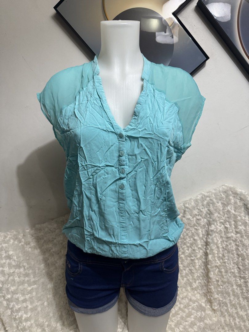 Light Blue V-Neck Button Front Blouse (Category: Blouses) located in Marikina City. Submitted by lorradel (Listing ID 1464903134, Image 2). Description: - Color: Light blue - Design: Sleeveless V-neck blouse with partial front buttons - Accents: Sheer chiffon details on shoulders and back yoke - Fit: Relaxed fit with a gathered elastic hem - Material: Lightweight, ideal for warm weather - Styling: Great to pair with shorts or jeans - MAY HAVE som