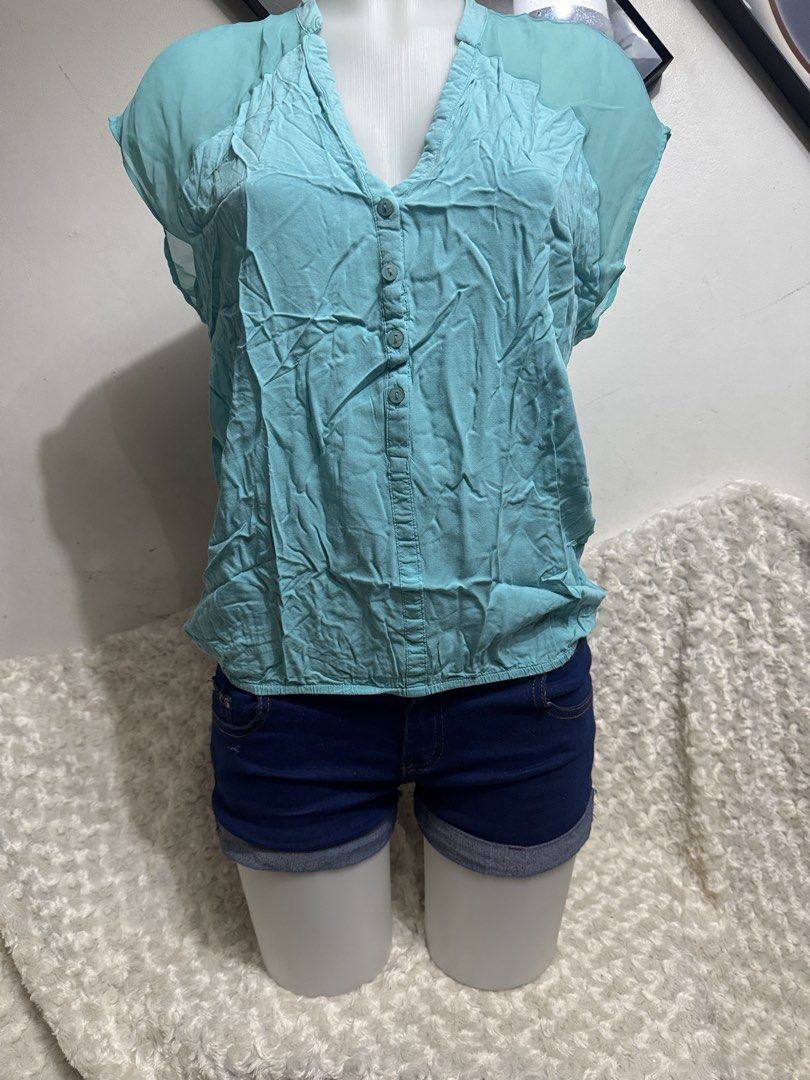 Light Blue V-Neck Button Front Blouse (Category: Blouses) located in Marikina City. Submitted by lorradel (Listing ID 1464903134, Image 3). Description: - Color: Light blue - Design: Sleeveless V-neck blouse with partial front buttons - Accents: Sheer chiffon details on shoulders and back yoke - Fit: Relaxed fit with a gathered elastic hem - Material: Lightweight, ideal for warm weather - Styling: Great to pair with shorts or jeans - MAY HAVE som