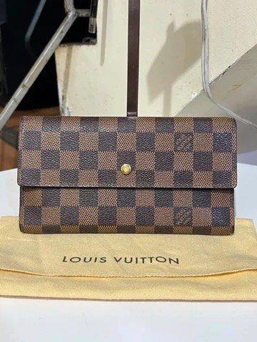 Louis Vuitton Damier Ebene Long Wallet (Category: Luxury Bags & Wallets) located in Quezon City. Submitted by luxuriesbymichiika (Listing ID 1464902835, Image 1). Description: - Authentic Louis Vuitton long wallet in iconic Damier Ebene canvas - Secure gold-tone snap button closure - Features multiple card slots and spacious flat compartments - Premium dark brown cross-grain leather lining - Includes original dust bag - Condition: Minor wear alon