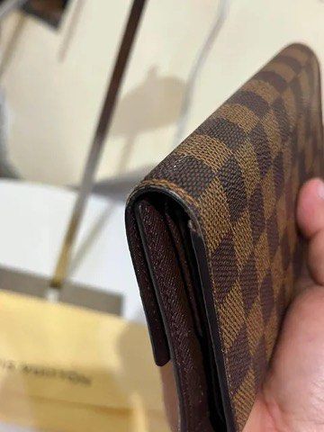 Louis Vuitton Damier Ebene Long Wallet (Category: Luxury Bags & Wallets) located in Quezon City. Submitted by luxuriesbymichiika (Listing ID 1464902835, Image 3). Description: - Authentic Louis Vuitton long wallet in iconic Damier Ebene canvas - Secure gold-tone snap button closure - Features multiple card slots and spacious flat compartments - Premium dark brown cross-grain leather lining - Includes original dust bag - Condition: Minor wear alon