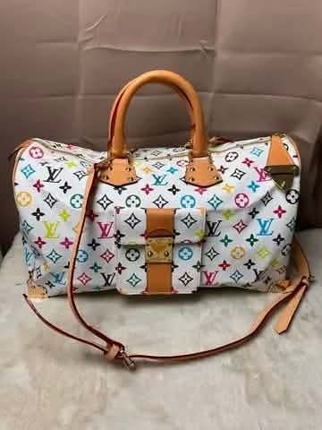Louis Vuitton Multicolor Monogram Travel Duffel Bag (Category: Luxury Bags & Wallets) located in Davao. Submitted by luckyturtle.aa6ccf (Listing ID 1464794985, Image 1). Description: - Brand: Louis Vuitton x Takashi Murakami - Design: Iconic white multicolor monogram with vibrant motifs - Material: Coated canvas with premium tan leather trim - Features: Double top handles, front zip pocket with buckle closure, and adjustable shoulder strap - Hard