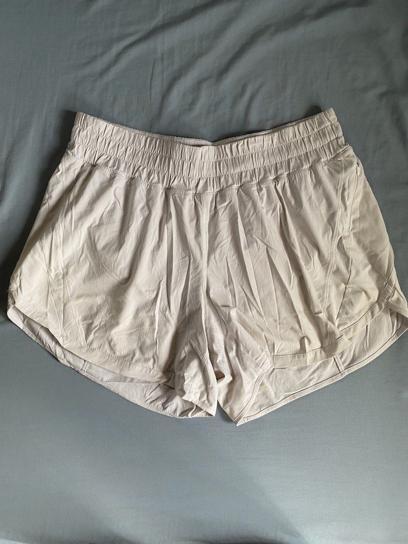 Lululemon High-Rise Track Shorts (Category: Shorts) located in Manila. Submitted by heyheyruok (Listing ID 1464797413, Image 1). Description: Lululemon Track That Short 5". High-rise waist with a wide elastic band. Soft neutral beige colorway. Built-in liner shorts inside. Secure zipper pocket on the side seam. Reflective logo detail near the bottom hem. Size 12 tag attached inside. Great everyday workout short..