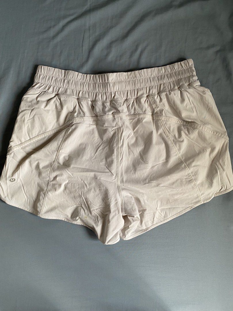 Lululemon High-Rise Track Shorts (Category: Shorts) located in Manila. Submitted by heyheyruok (Listing ID 1464797413, Image 3). Description: Lululemon Track That Short 5". High-rise waist with a wide elastic band. Soft neutral beige colorway. Built-in liner shorts inside. Secure zipper pocket on the side seam. Reflective logo detail near the bottom hem. Size 12 tag attached inside. Great everyday workout short..
